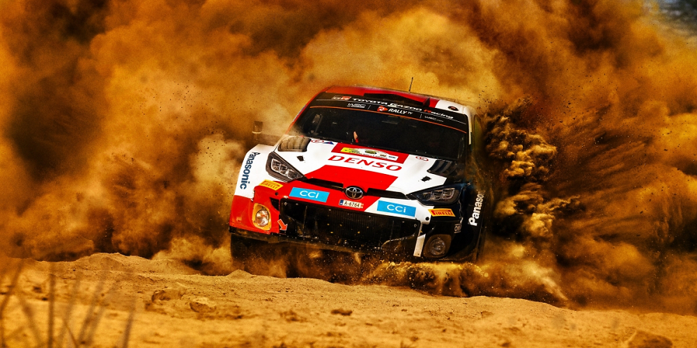 Ein Rallye-Auto rast über die Piste und wirbelt Staub auf