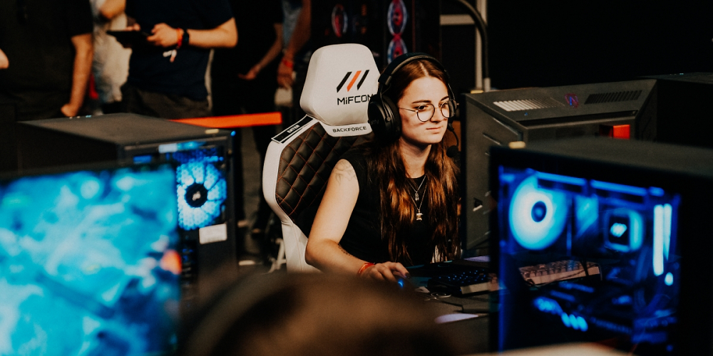 Spielerin sitzt an PC, Spiel im Vordergrund