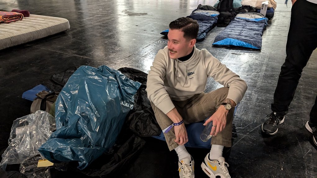 Mann auf einer Isomatte neben einem Müllsack