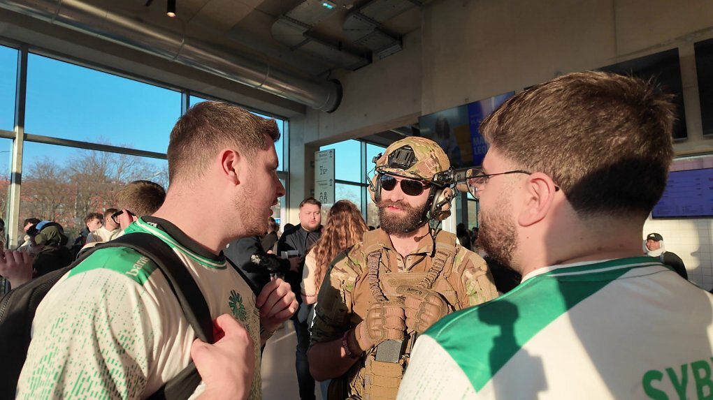 Ein Cosplayer unterhält sich mit zwei Fans in Trikots.
