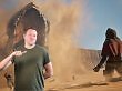 Ein Sandwurm schießt aus dem Sand, ein Mensch kniet flehend am Boden