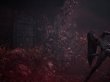 Ein mit roten Pflanzen überwuchertes Haus in Silent Hill f. rechts steht eines der Puppen-Monster.