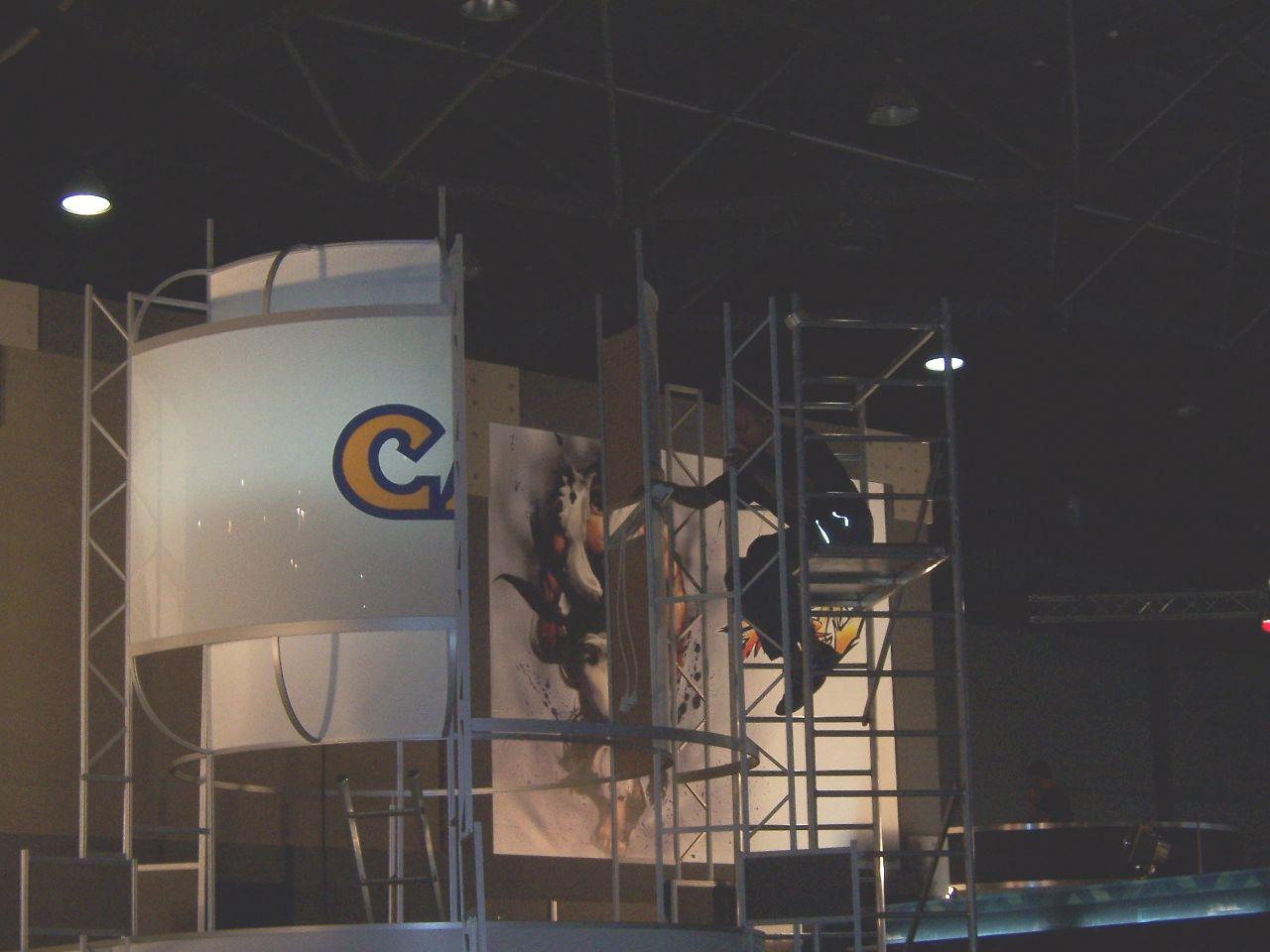 [18/08/2008] Ein Stand entsteht, hier der von Capcom. Baugerüst, Leiter und Kran bestimmen derzeit noch das Bild der Messehallen. Die Geräuschkulisse, derzeit noch Hämmern, Sägen und Bohren wird sich bald wandeln - in den Hallen herrscht traditionell ein irrer Lärmpegel aus Musik, Spiele-Trailern und Bühnenshows, alles über wuchtige Lautsprecher in die Umgebung geblasen.