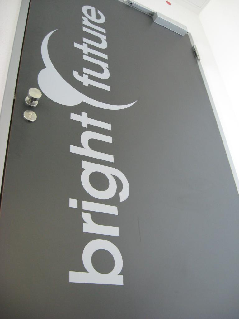 [17/11/2009] Hier sehen wir die eindrucksvolle Eingangstür zu den heiligen Hallen von Bright Future. Selbstverständlich wurden nur Hölzer aus ökologischer Forstwirtschaft zur Herstellung genutzt, das klassische Firmenlogo in grau auf grau zeugt von Stilsicherheit und Geschmack.