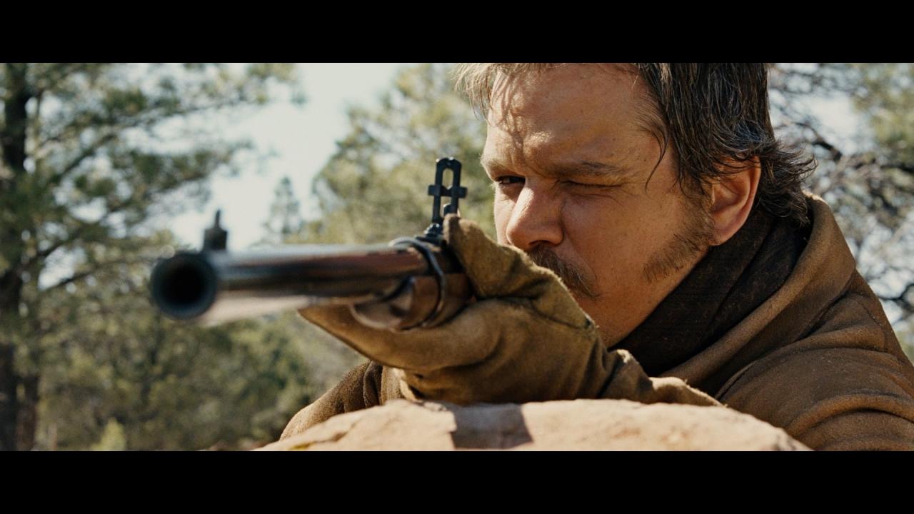 Matt Damon in der Rolle des Texas-Rangers LaBoeuf blickt durch das Visier des Karabiners von Marshal Cogburn.