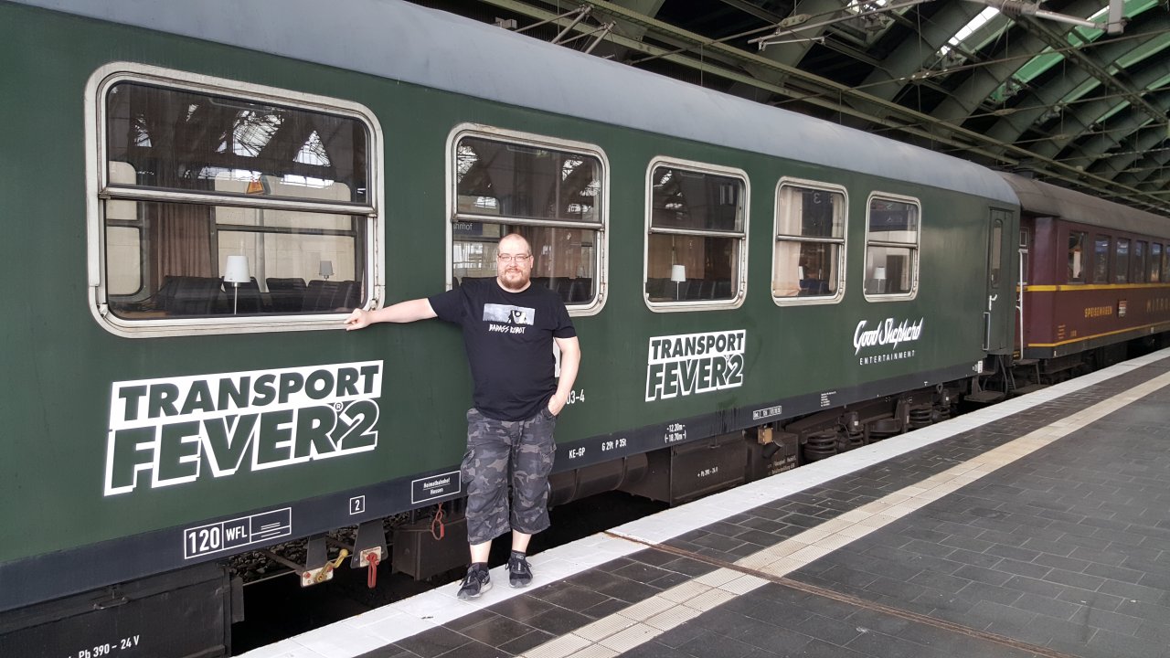 [08/07/2019] Ein Vorschau-Event der etwas anderen Art.Um Transport Fever 2 erstmals der Presse vorzustellen, haben Entwickler, Publisher und PR-Agentur nicht einfach in irgendwelche Büros, Meeting-Räumen oder Event-Locations eingeladen. Stattdessen hat man sich etwas ganz Besonderes ausgedacht. Ziel unserer Einladung war zunächst der Berliner Ostbahnhof, direkt an der Spree in der Nähe der East-Side-Gallery gelegen. Dort stand ein Sonderzug aus alten Personen- und Mitropa-Wagen der Deutschen Reichsbahn der ehemaligen DDR bereit. Ursprünglich war sogar geplant, dass der historische Zug stilecht von einer Dampflok gezogen wird. Das war aber kurzfristig aufgrund der heißen Temperaturen und der damit verbundenen hohen Waldbrandgefahr leider nicht möglich. Mit der Journalistenmeute und einer handvoll Entwickler an Bord drehte der Zug den ganzen Tag seine Runden durch das Berliner Umland. Im Inneren hatten die Veranstalter einen ganzen Wagon mit Laptops ausgestattet, wo wir ausgiebig Transport Fever 2 anspielen konnten. Im Mitropa-Speisewagen gab es dann die Gelegenheit, bei erfrischenden Getränken mit den Entwicklern zu plaudern.