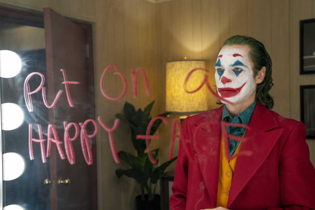 Joaquin Phoenix blickt als Joker in einen Spiegel.