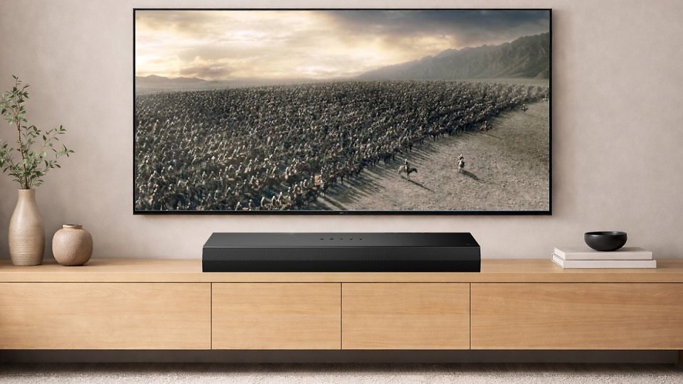Ein TV hängt an der Wand und zeigt Herr der Ringe, darunter steht eine Soundbar.